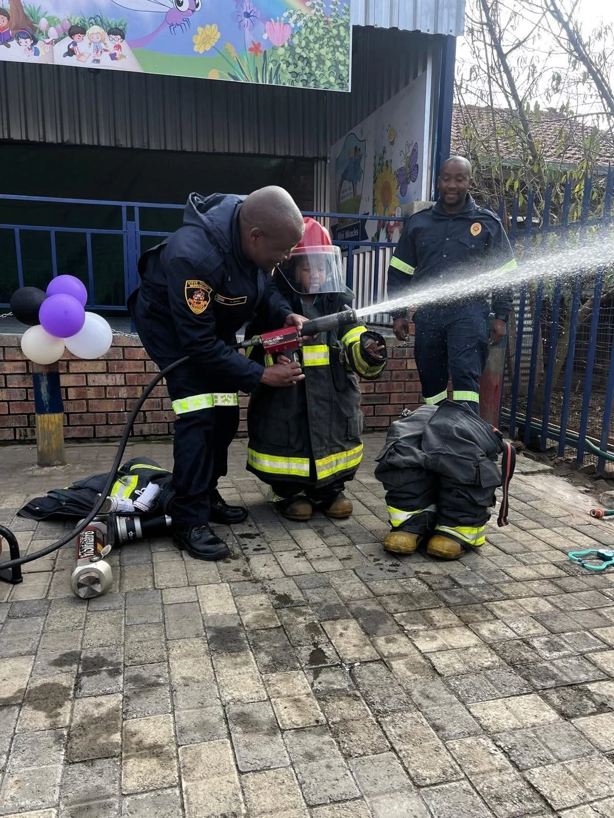 Children trying a fire hose with a firefighter