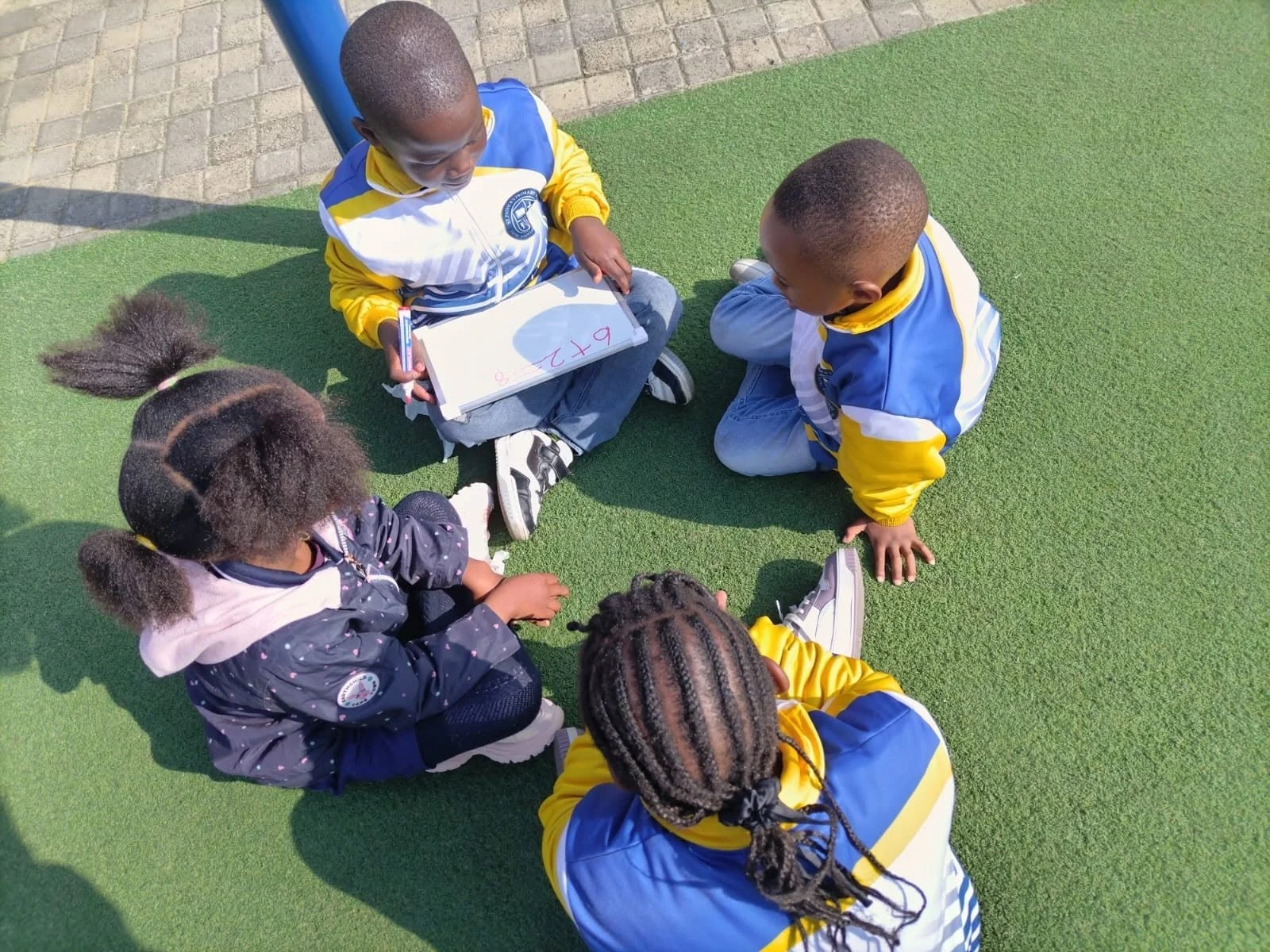 A small group practising number work on a whiteboard outdoors